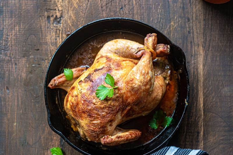 A golden-brown whole roast chicken resting on a wooden board.